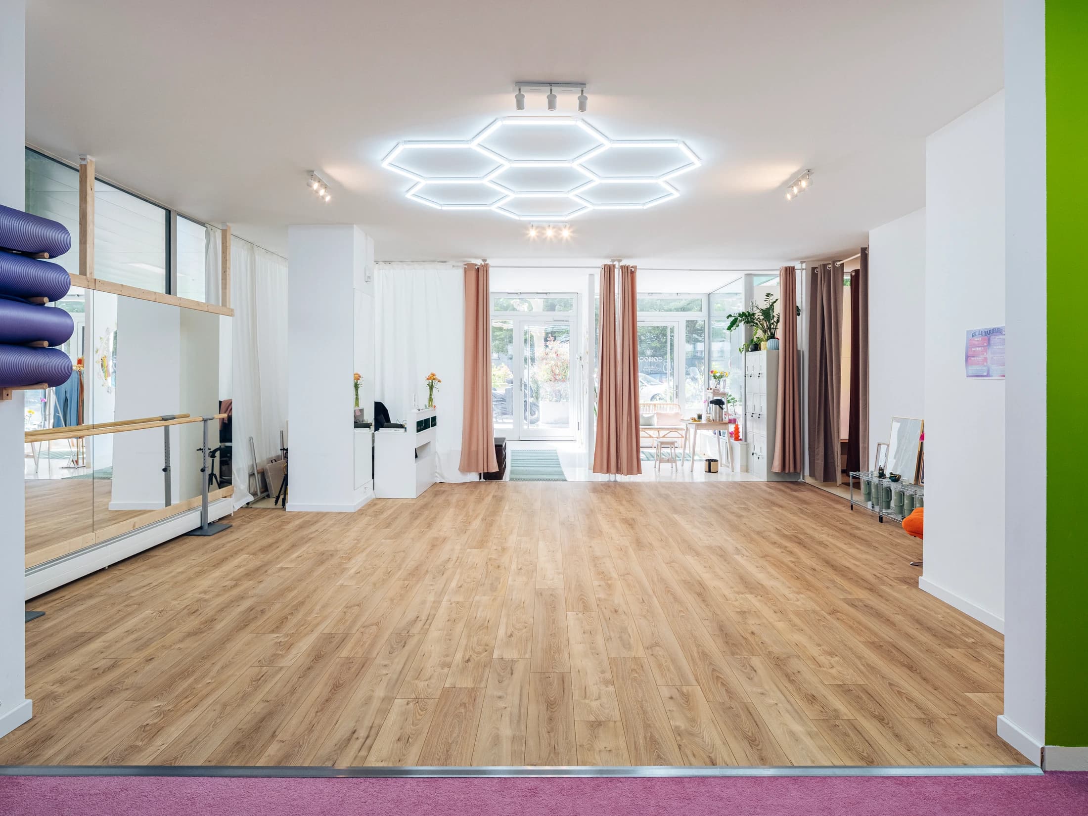 Grande salle de danse COMOCO — sol parquet, plafond hexagonal lumineux, lumière naturelle entrant par les vitrines
