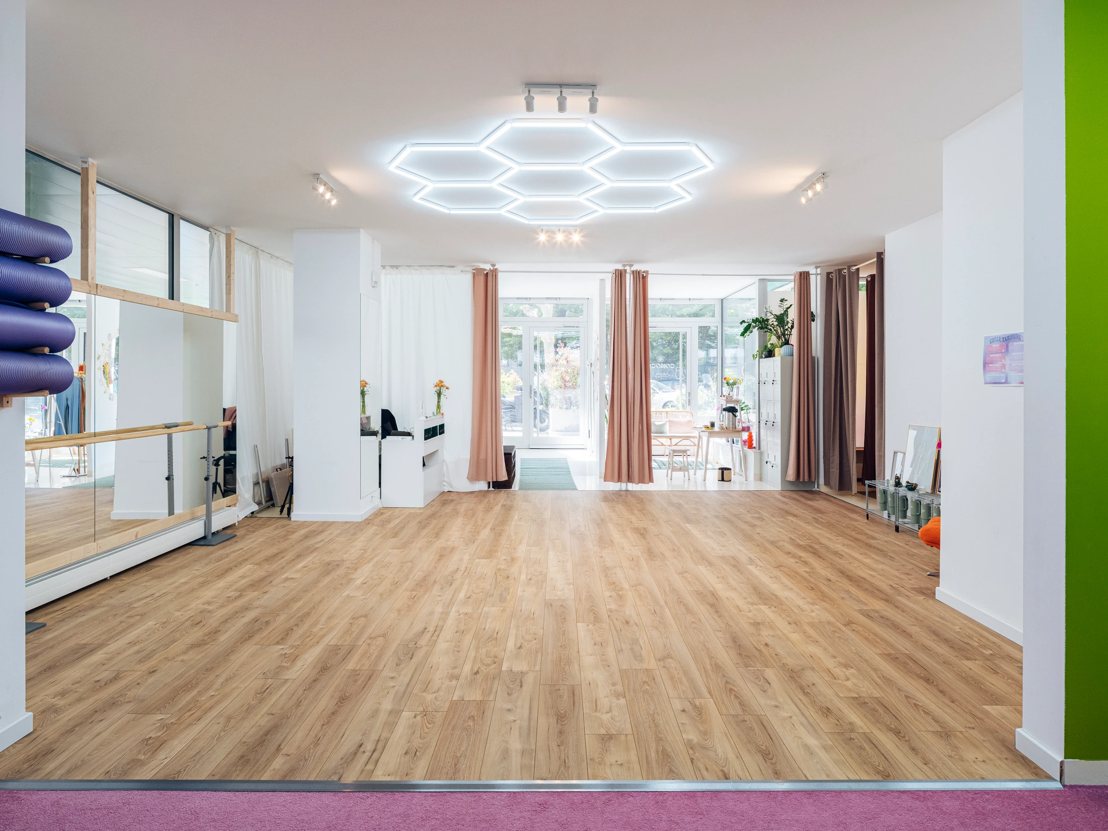 Grande salle de danse COMOCO : sol parquet, plafond hexagonal lumineux, lumière naturelle entrant par les vitrines